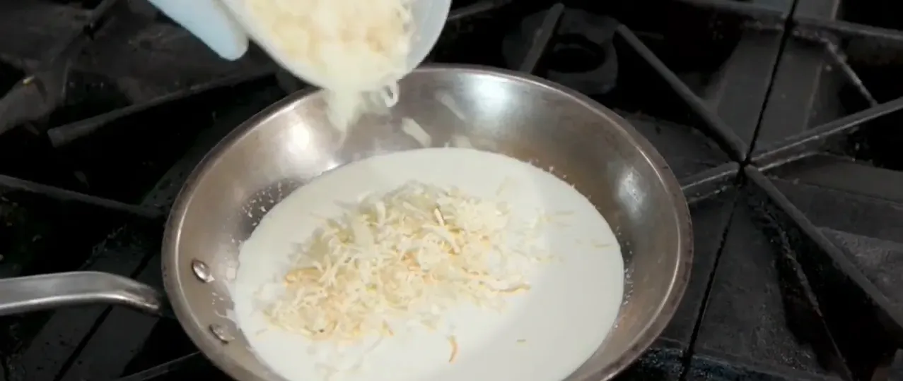 Pouring housemade garlic cream into pan to make mac and cheese