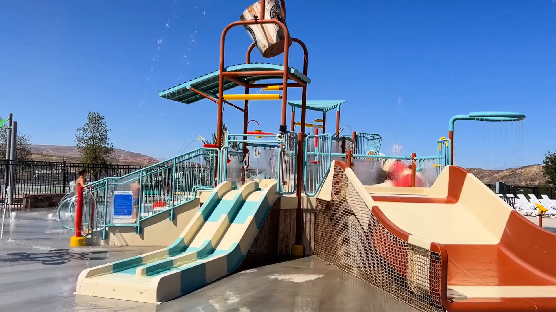 Families enjoying water slides and splash pad area at the park